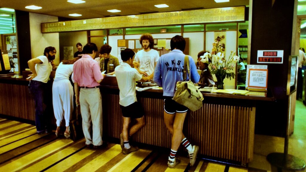 students gathered at the Olin Library information desk, 1983